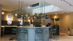 Un espace bar moderne doté d’un bar circulaire, de nombreux tabourets et de plantes en pot.