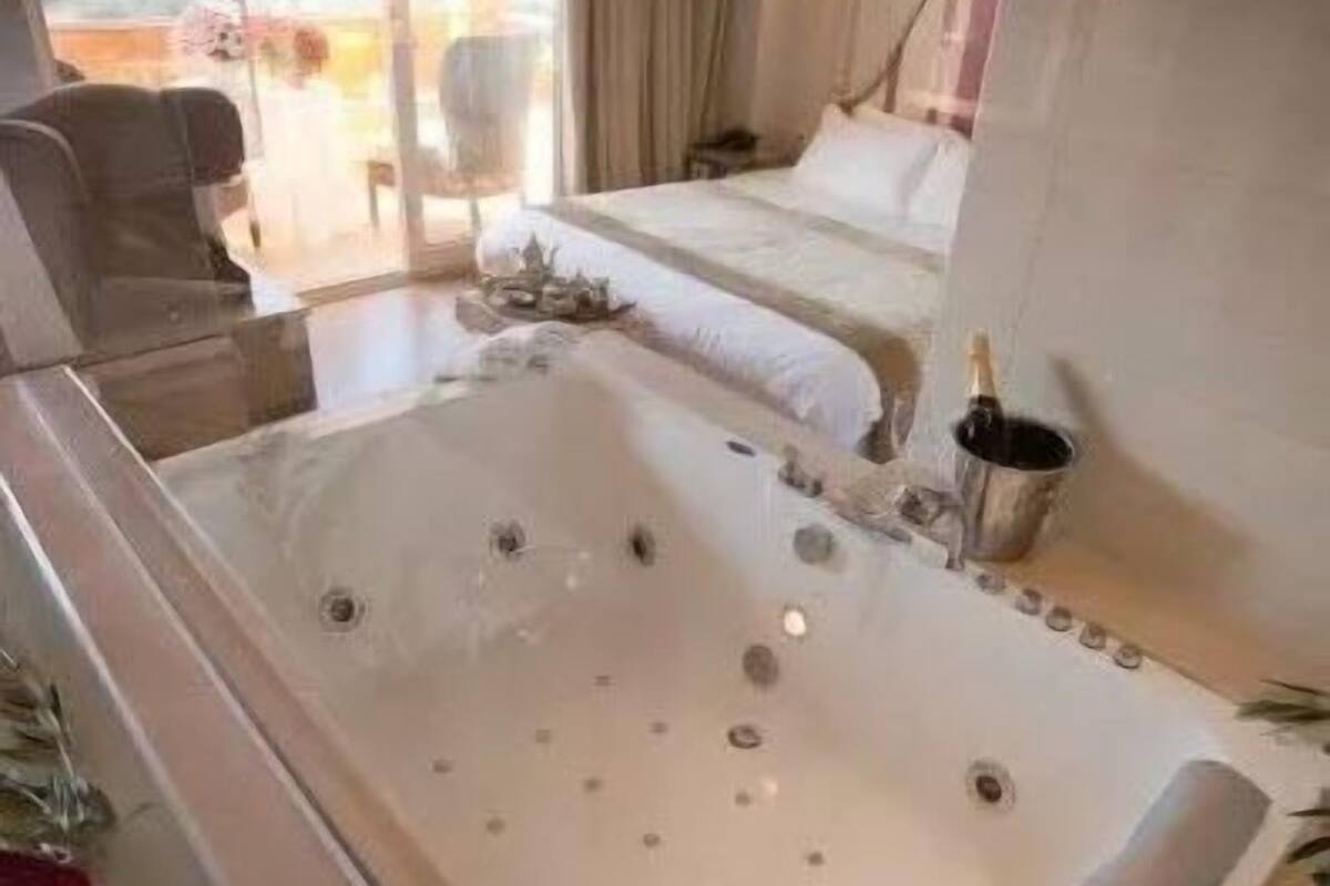 Ein modernes Hotelzimmer mit einer großen Badewanne, einem Bett und Blick ins Freie.