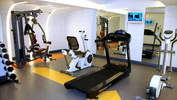 Un gimnasio con diversos equipos de ejercicio, incluyendo una cinta de correr, bicicleta estática y máquinas de pesas.