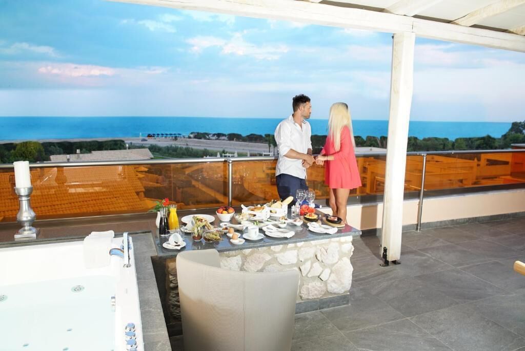 A couple dining on a terrace with a view of the sea.