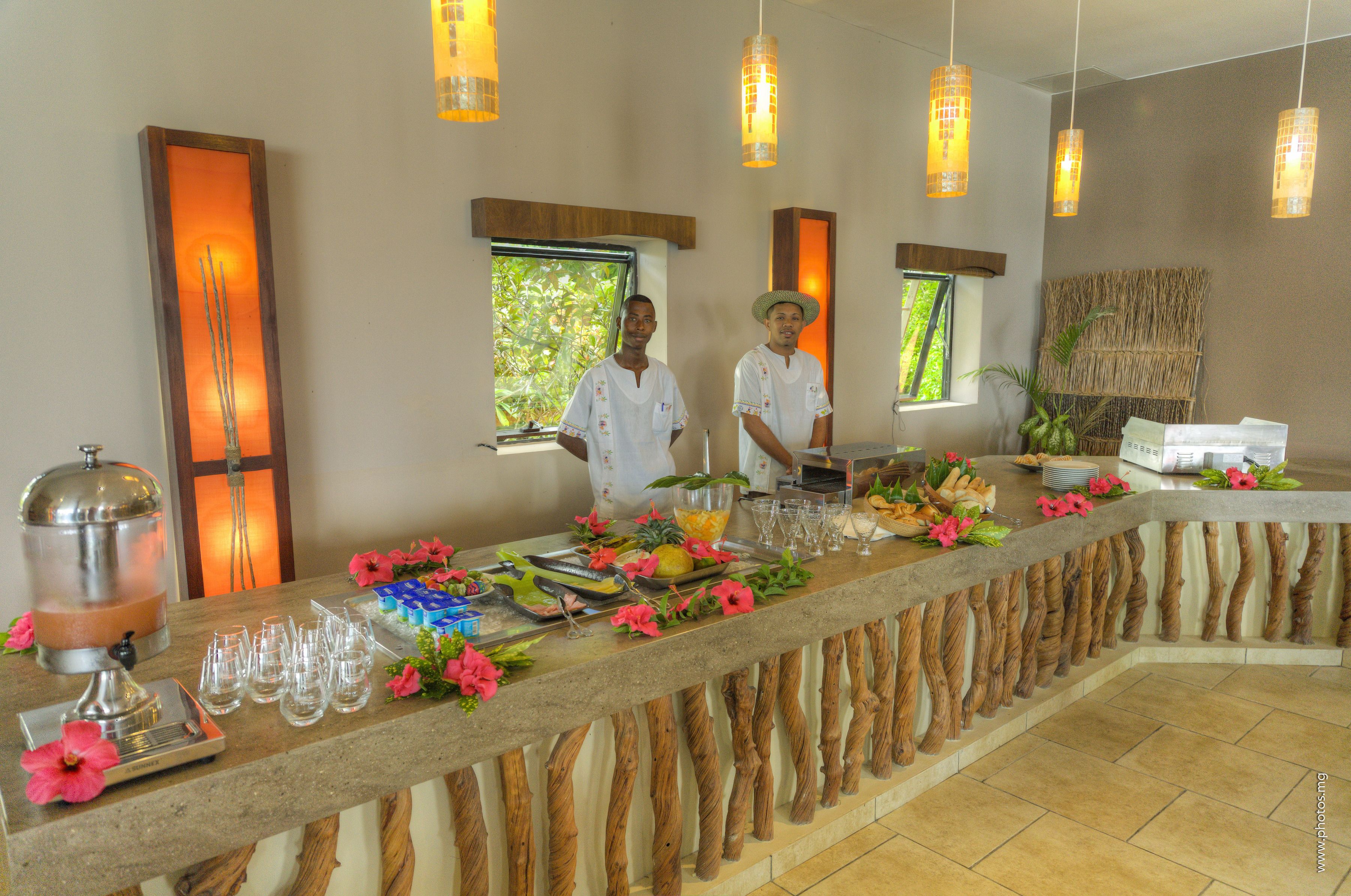 Una mesa de buffet con dispensador de bebidas, fruta y cristalería.
