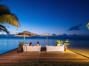A wooden deck with two white lounge chairs and umbrellas, overlooking a calm body of water. - Mantis Soanambo Hotel and Spa (Nosy Boraha)