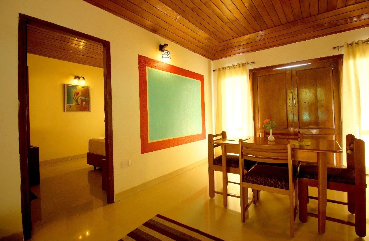 Un comedor con una mesa y sillas de madera, un cuadro en la pared y una ventana con cortinas.
