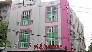 Un edificio de varios pisos con fachada rosa y gris, ventanas grandes y un letrero con caracteres chinos.