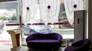 Una habitación con un sofá morado, una mesita y una ventana con cortinas.
