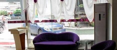 A room with a purple sofa, a small table, and a window with curtains.