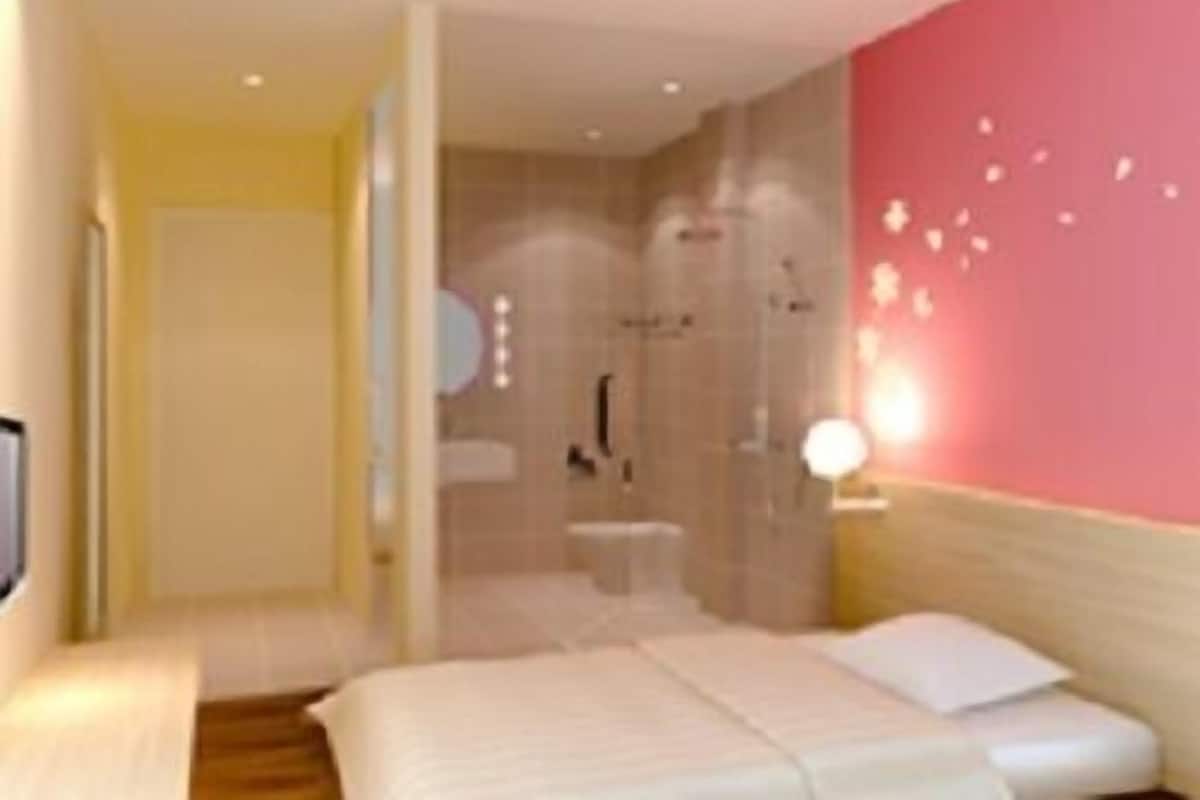 Una habitación de hotel con cama, baño y zona de ducha.