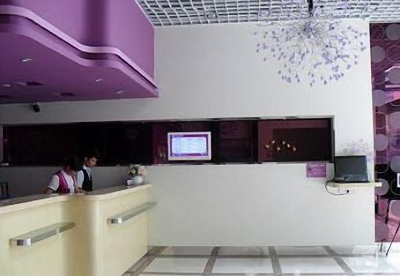 Un área de recepción con mostrador, pantalla de televisión y un candelabro decorativo.