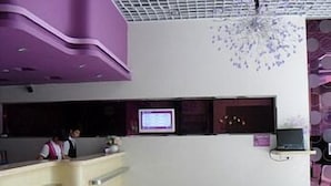 Un área de recepción con mostrador, pantalla de televisión y un candelabro decorativo.