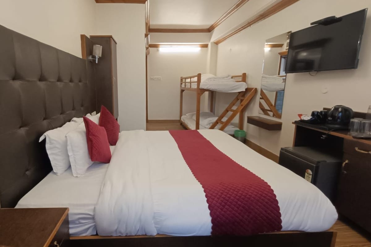 A hotel room with a large bed, a television, a desk with a chair, and a wardrobe.
