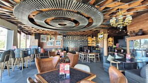 Ein Restaurant mit modernem Interieur, das sich durch ein einzigartiges Deckenkonzept, Holztische und -stühle auszeichnet.