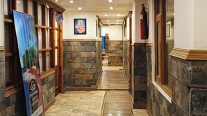 A hotel corridor with stone walls, wooden benches, and a wooden walkway. - Bridge View Regency (Shimla)