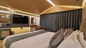 A modern hotel room with a large bed, a flat-screen TV, a desk, and a comfortable seating area. - Bridge View Regency (Shimla)