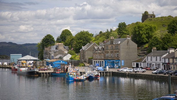A harbor with boats, a lighthouse, and buildings along the waterfront. - Knap Guest House (Tarbert)