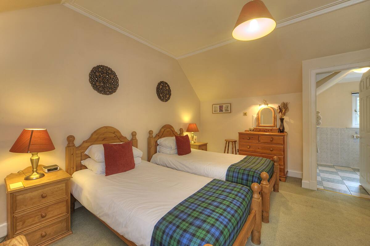 A bedroom with two wooden beds, nightstands, a dresser, and a mirror.