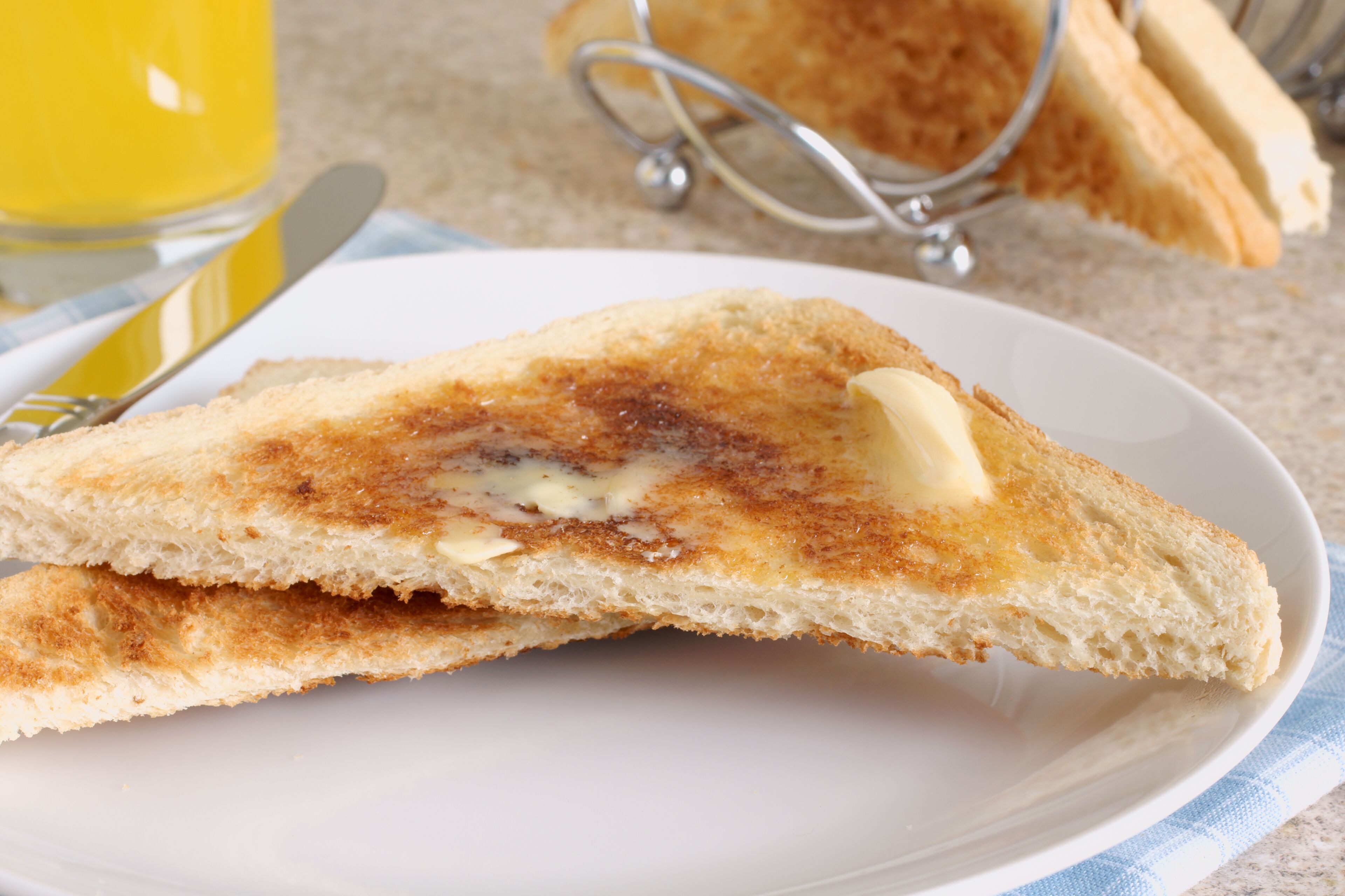 Un plato con un sándwich tostado y un vaso de zumo de naranja.