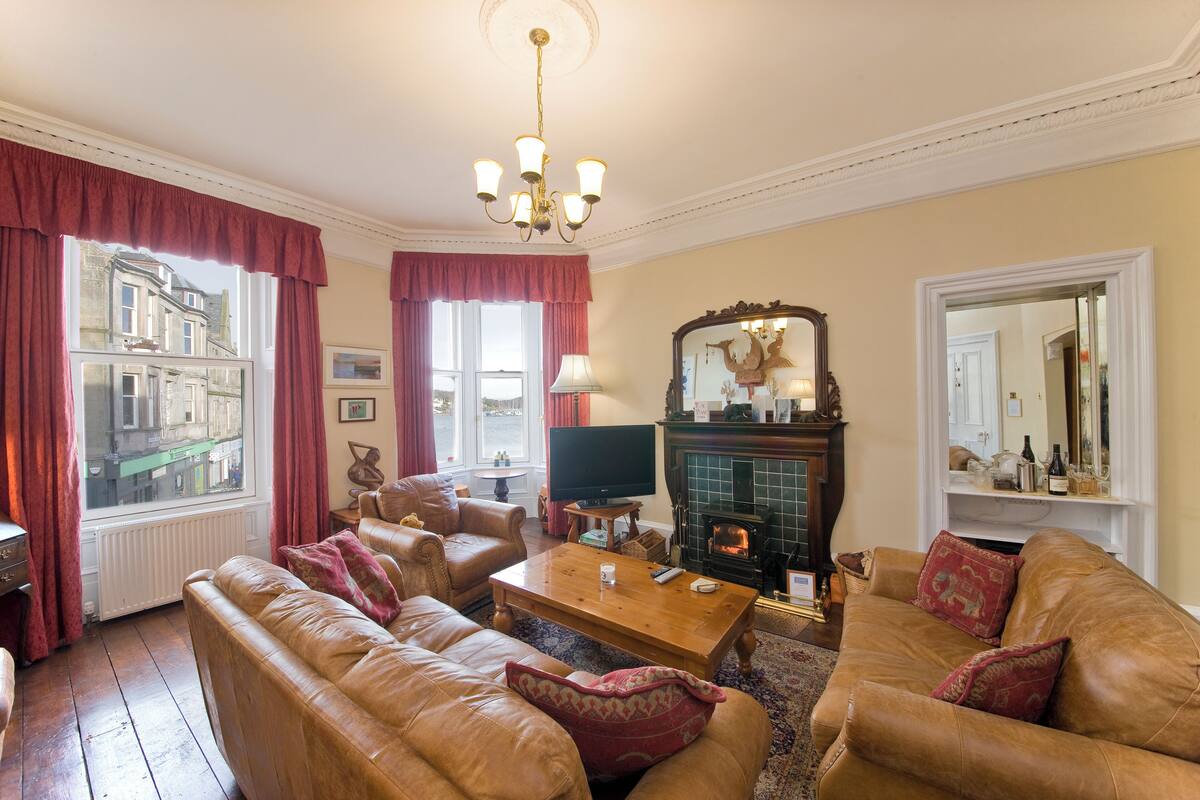 A cozy living room with leather sofas, a wooden coffee table, a fireplace, and a television.