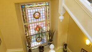 A staircase with a white balustrade, a stained glass window, and a potted plant. - Knap Guest House (Tarbert)