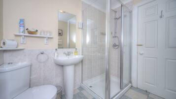 Een badkamer met toilet, wastafel en douche met glazen wanden.