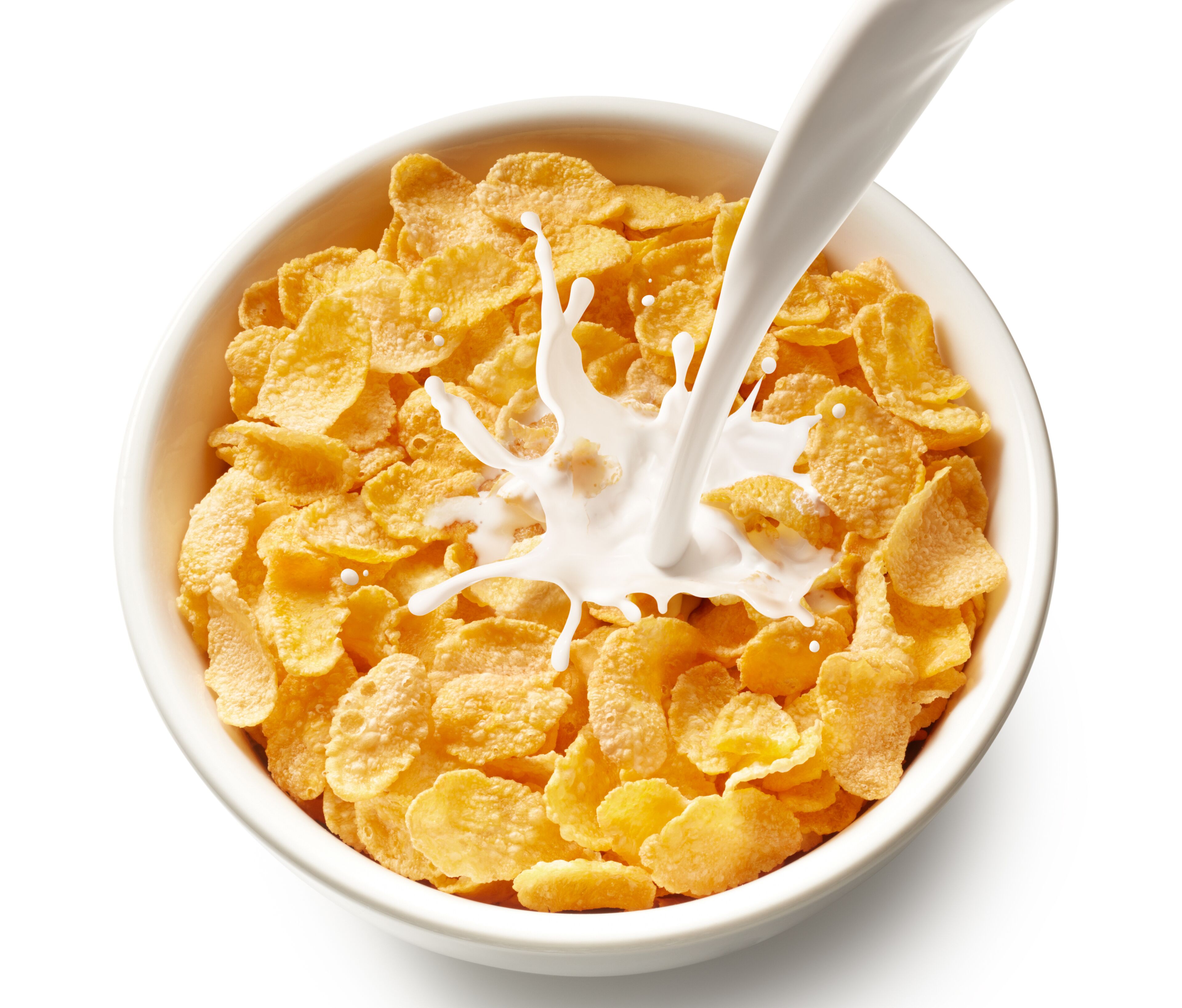 A bowl of cornflakes with milk being poured into it.