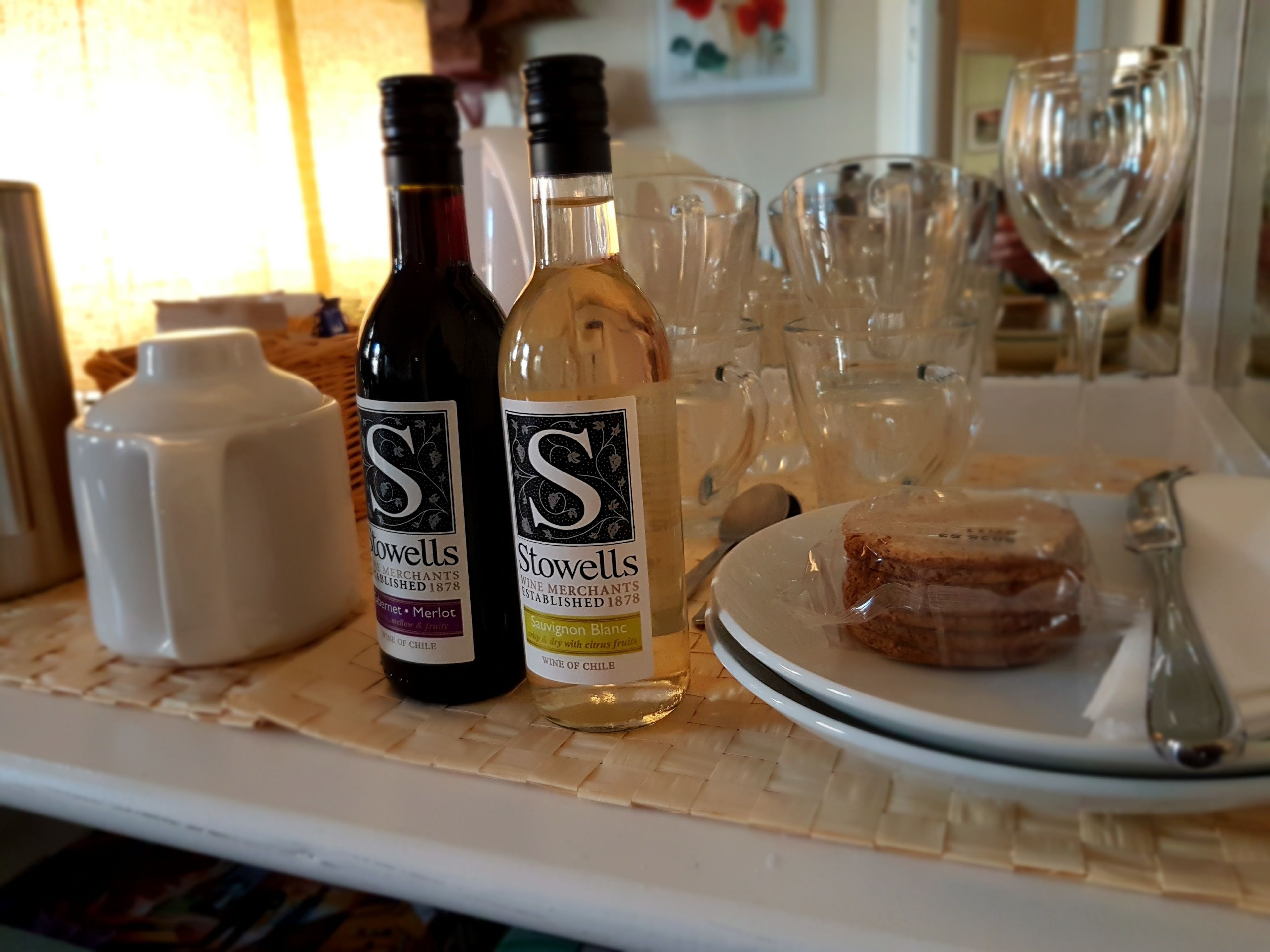 Una mesa con botellas de vino, copas y un plato de comida.