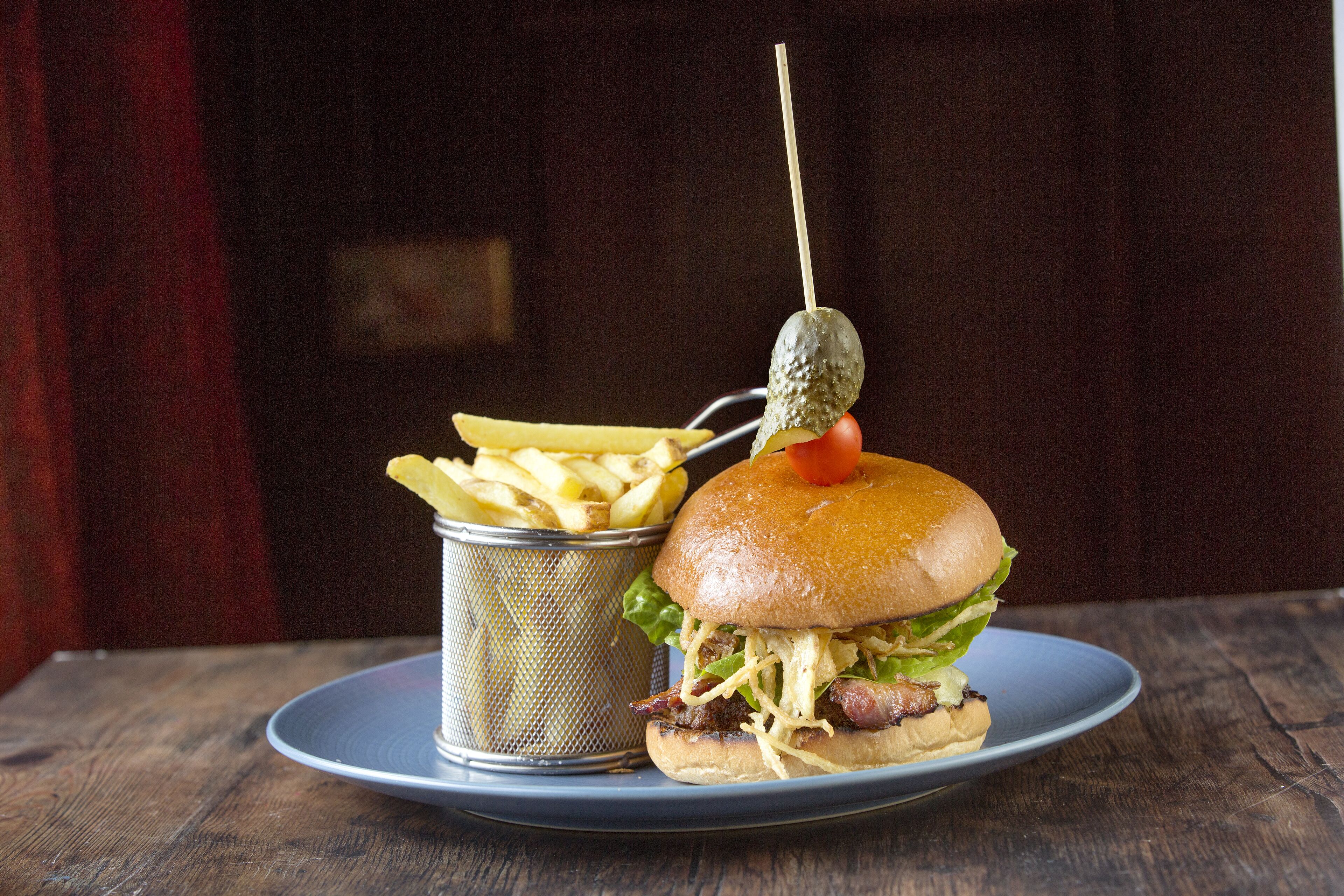 A plate with a burger and a container of fries.