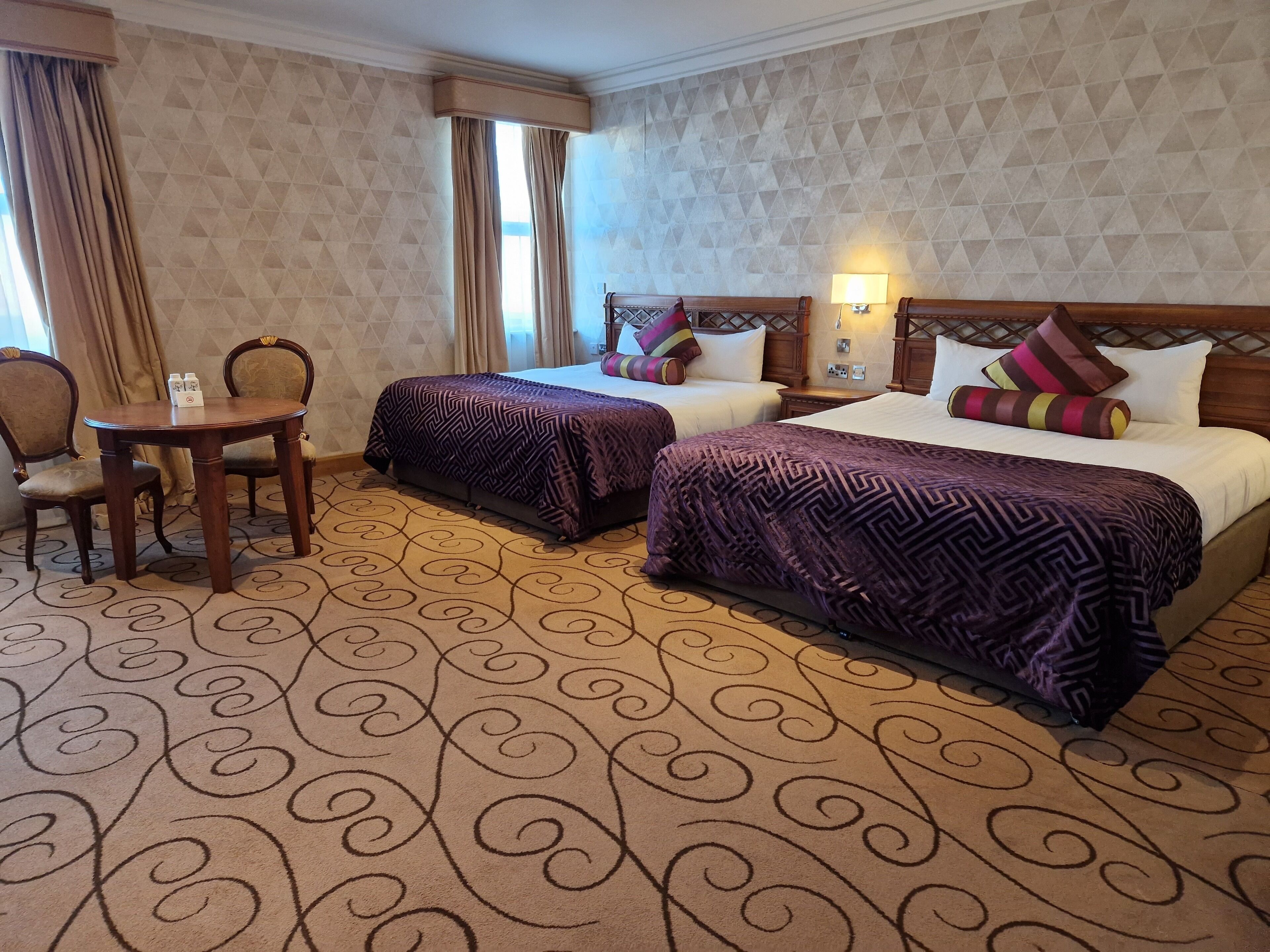 Ett hotellrum med två sängar, ett matbord och en stol.