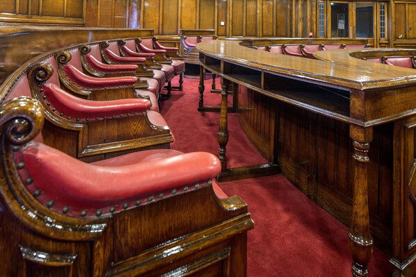 Una sala de reuniones formal con una larga mesa de madera y sillas tapizadas en rojo.