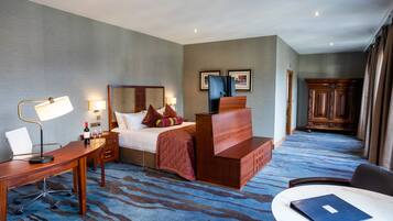 A hotel room with a bed, desk, chair, and a small table.