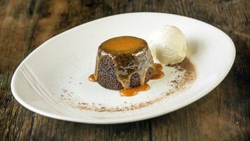 A dessert on a white plate with caramel sauce and a scoop of ice cream.