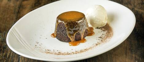 A dessert on a white plate with caramel sauce and a scoop of ice cream.