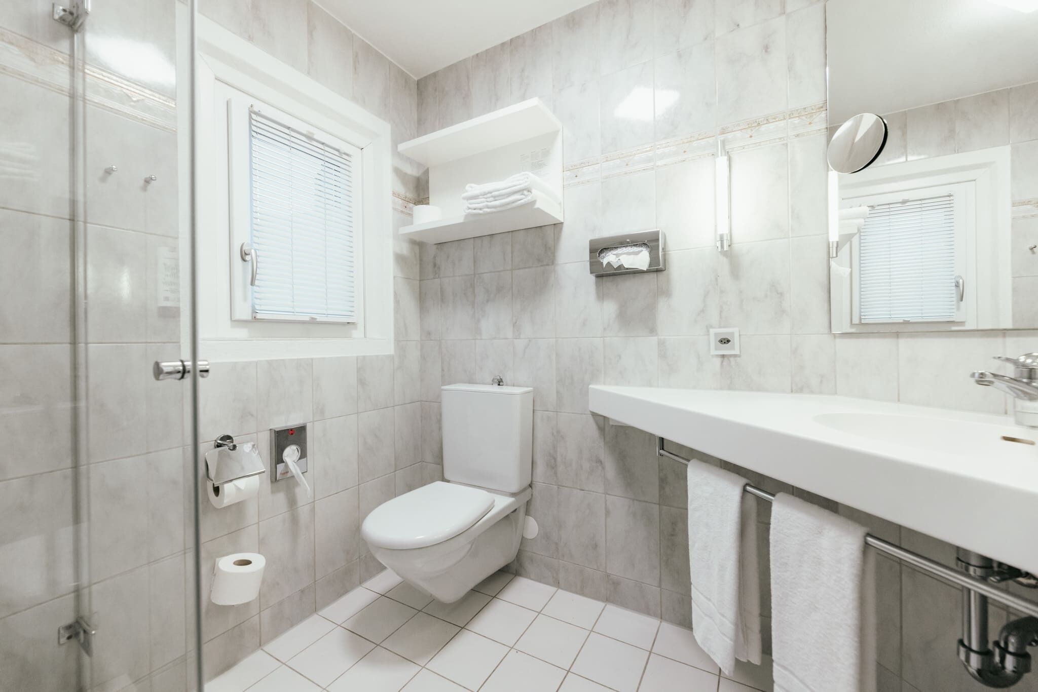 A modern bathroom with a toilet, sink, and glass shower enclosure.
