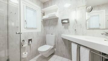 Un baño moderno con inodoro, lavamanos y cabina de ducha con mampara de vidrio.