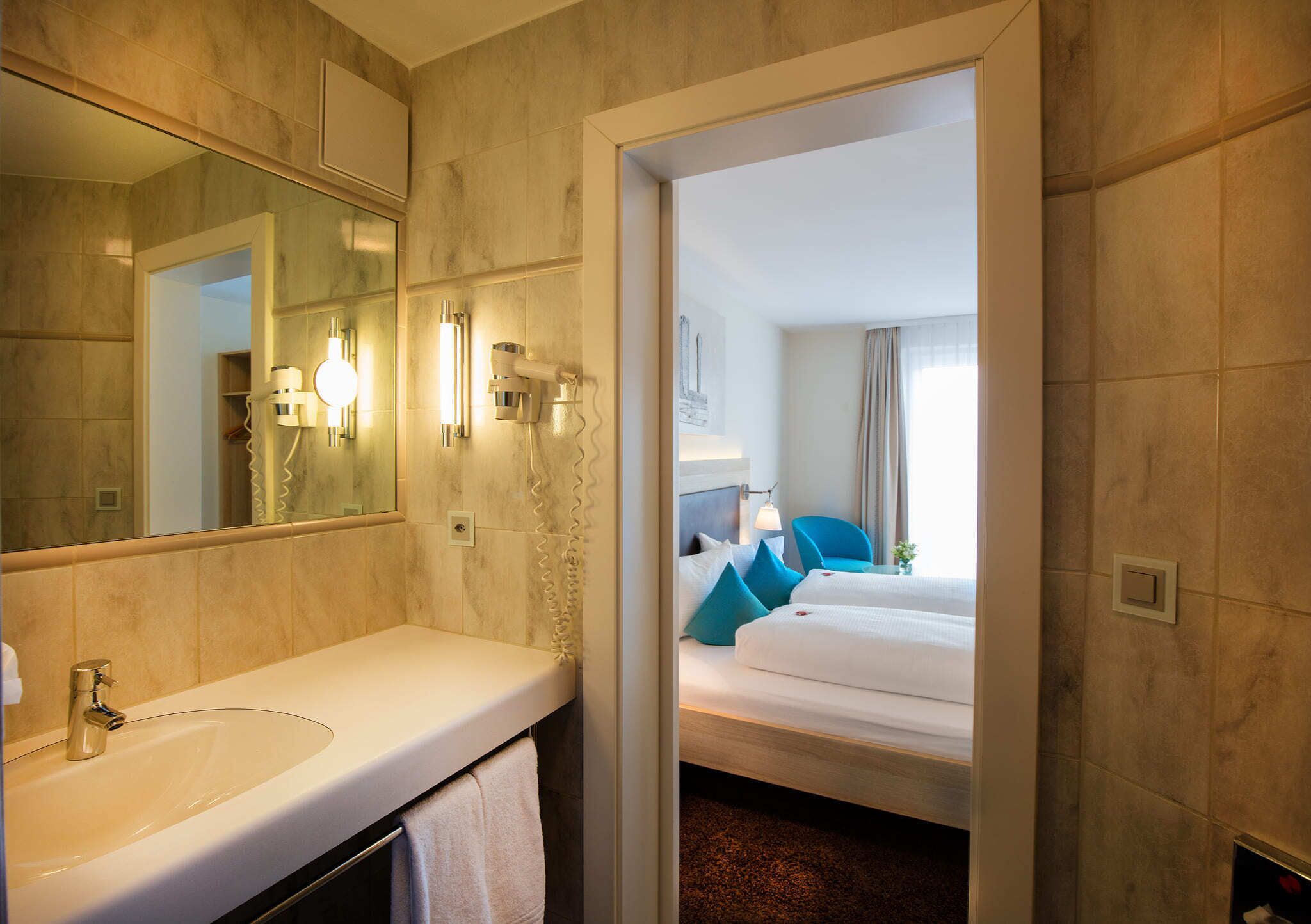 Un baño de hotel con lavabo, espejo y toallero.