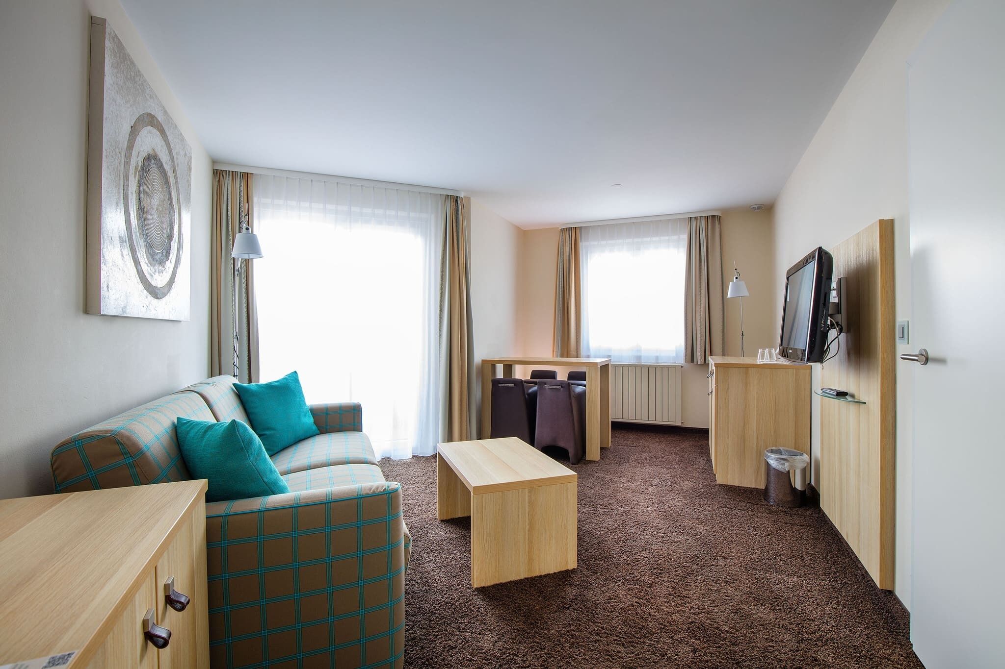 Une chambre d’hôtel de taille réduite, comprenant un canapé, une petite table, un téléviseur et un espace bureau.