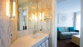 A modern bathroom with a large mirror, a sink, and a hairdryer.