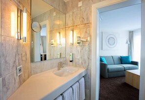 Une salle de bain moderne avec un grand miroir, un lavabo et un sèche-cheveux.
