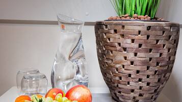 A table with a fruit bowl, a pitcher, and a potted plant.