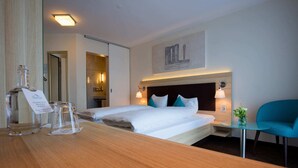 Une chambre d’hôtel avec un grand lit, des lampes de chevet, une petite table avec un vase et un miroir.
