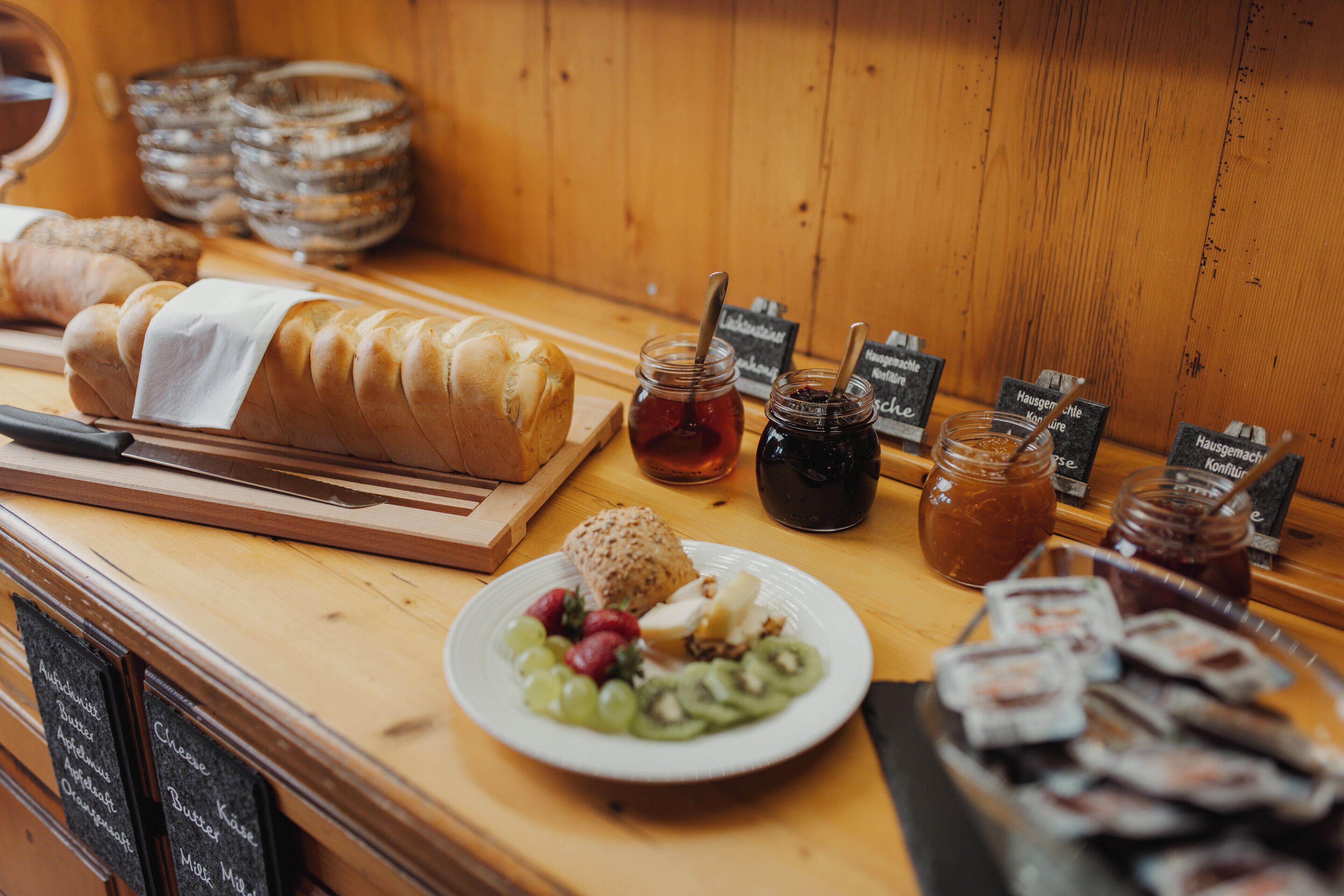 A breakfast buffet with various breads, jams, and fruits.