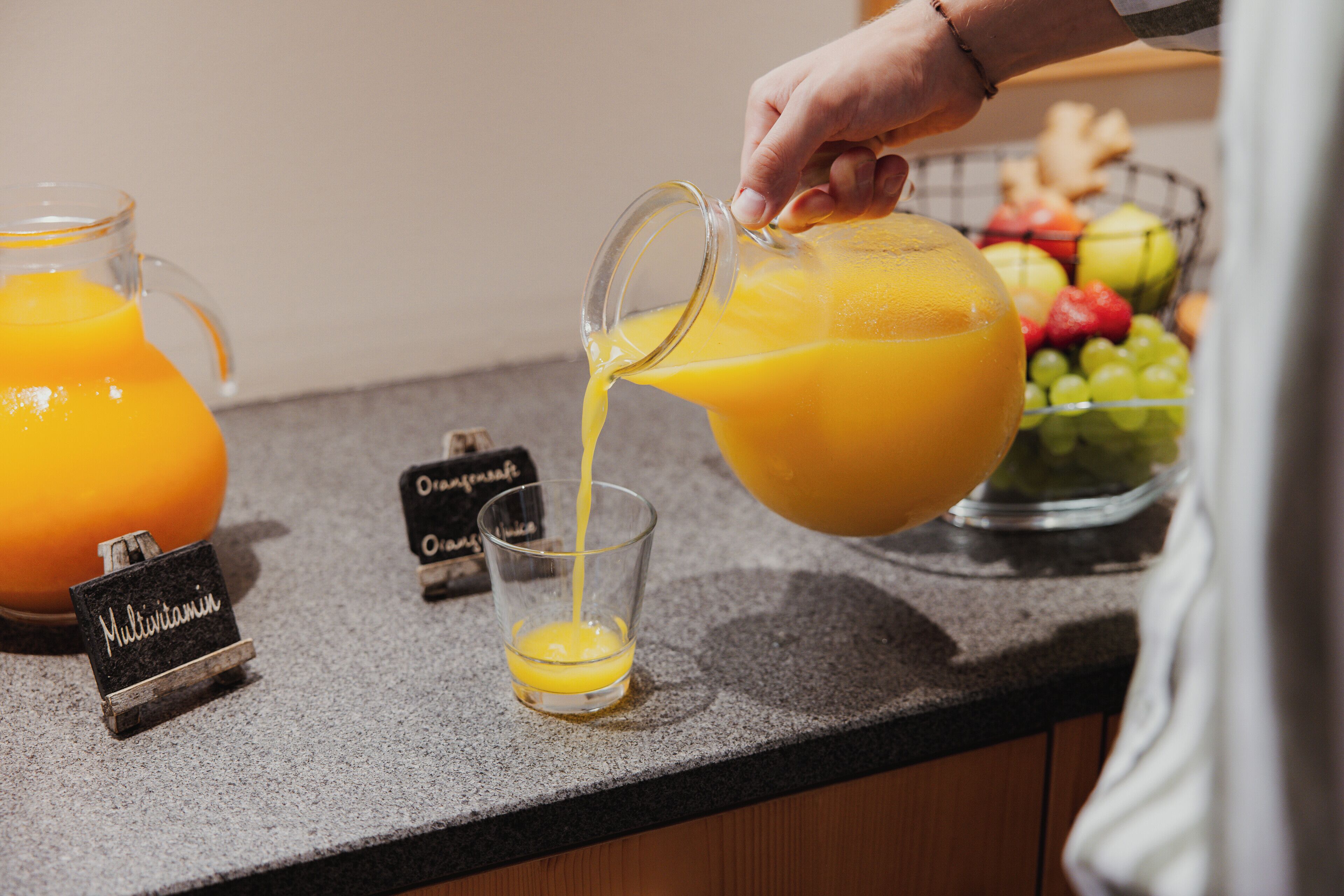 Una mano vertiendo jugo de naranja en un vaso.
