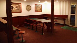 Une pièce avec une table de billard, des tabourets de bar et une horloge au mur.