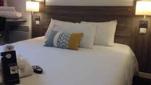 Une chambre d’hôtel avec un grand lit, deux lampes de chevet, une table de chevet et un téléviseur fixé au mur.