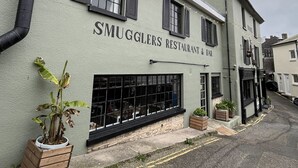 Un edificio con un cartello che riporta la scritta 'SMUGGLERS RESTAURANT & BAR'.