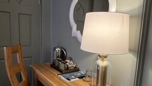 Una scrivania in legno con una lampada, una sedia, uno specchio e una porta.