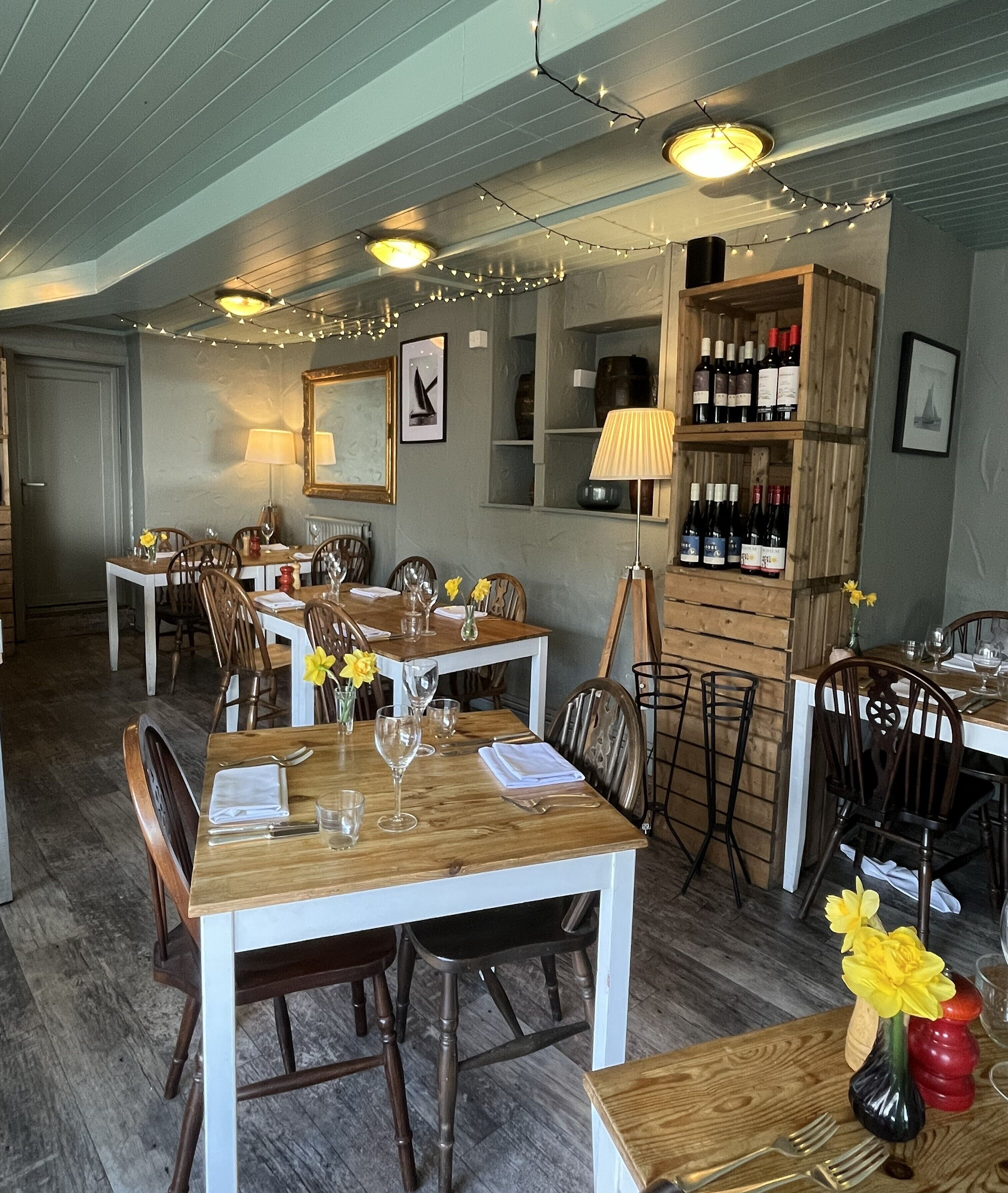 A restaurant with wooden tables, chairs, and a wine rack.