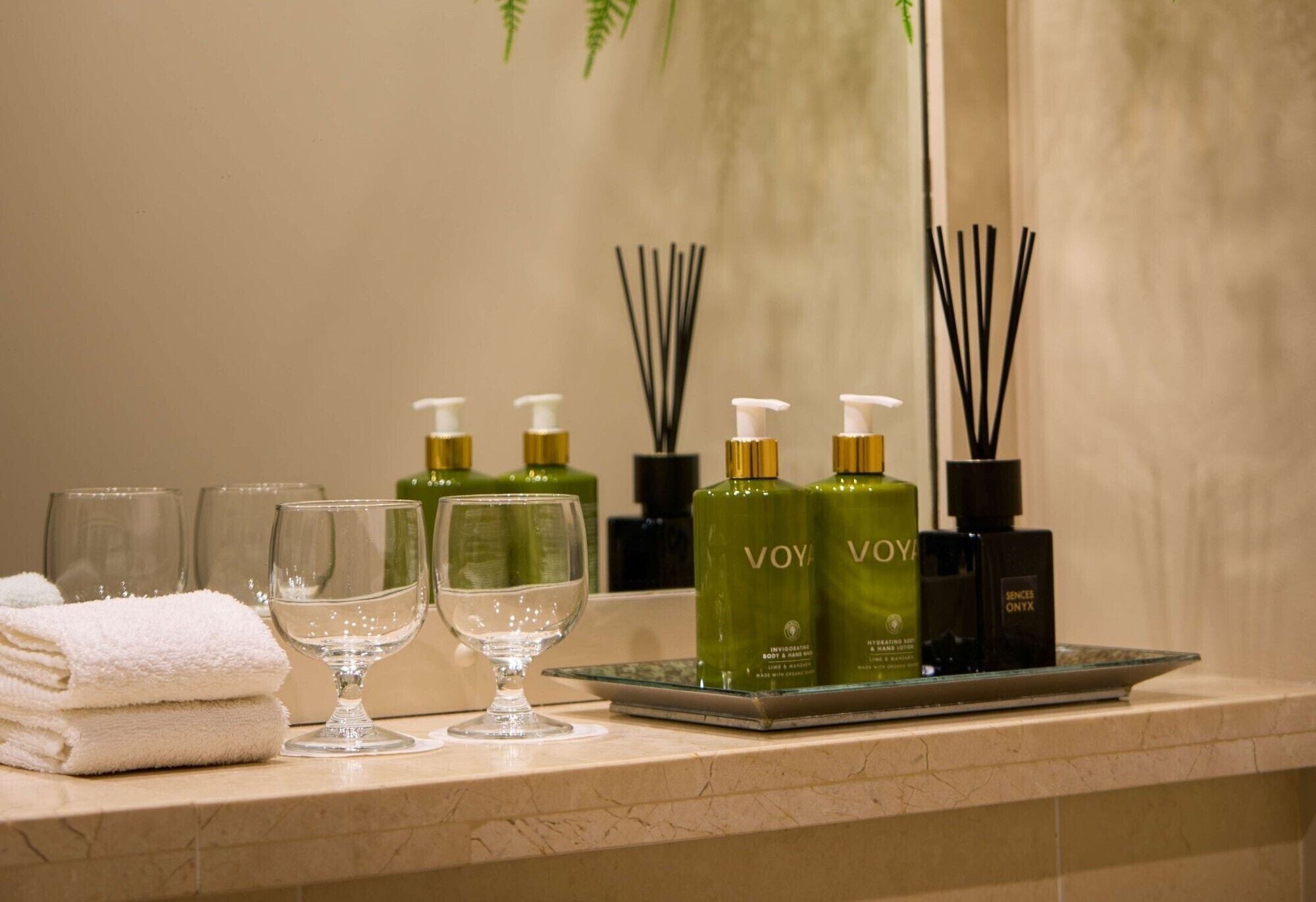 A bathroom vanity with toiletries, a towel, and two glasses.