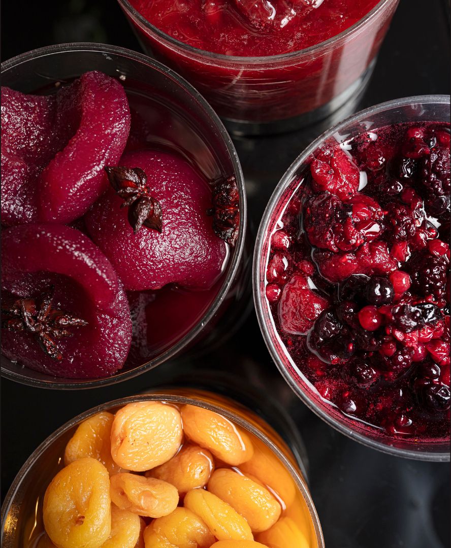 Four glass containers filled with different types of preserved fruits.