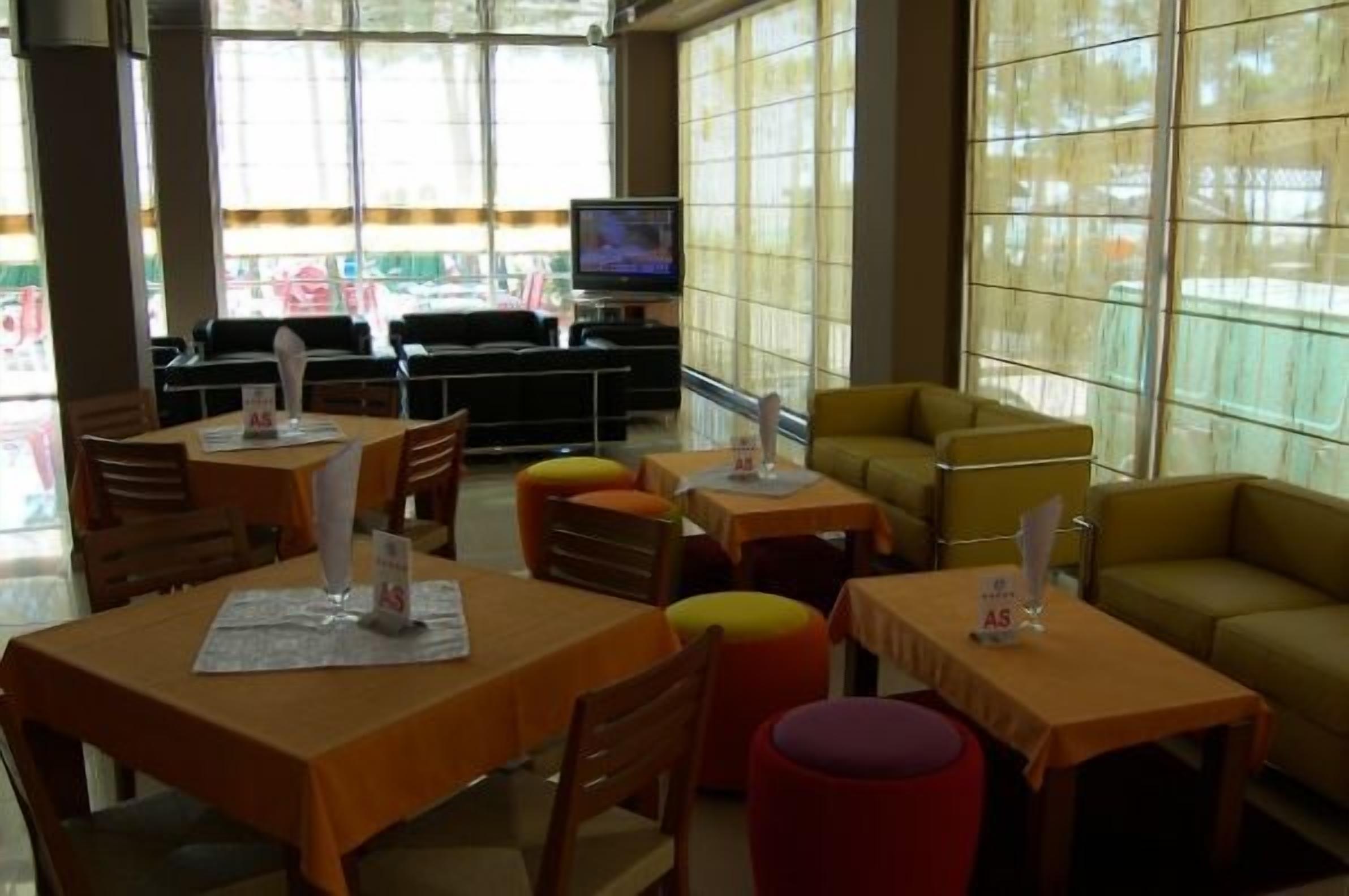 Ein Restaurant mit Tischen, Stühlen, einem Fernseher und großen Fenstern.