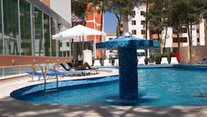 A swimming pool with lounge chairs and umbrellas, surrounded by buildings. - AS Hotel (Golem)